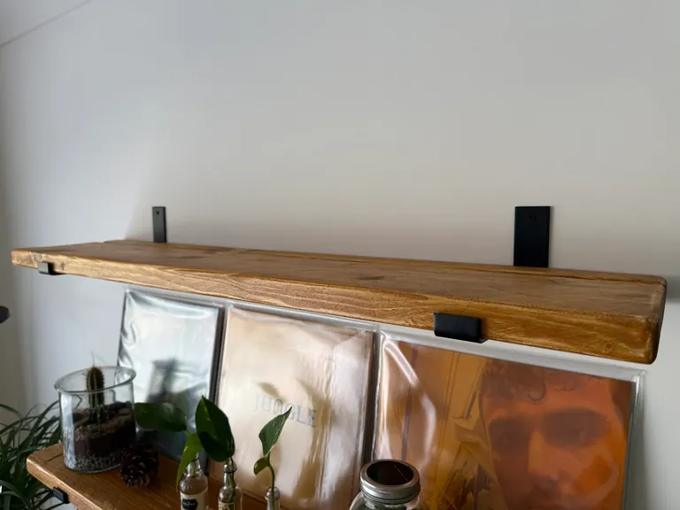 Antique pine shelf showing the timber grain, softened front edge and black steel brackets